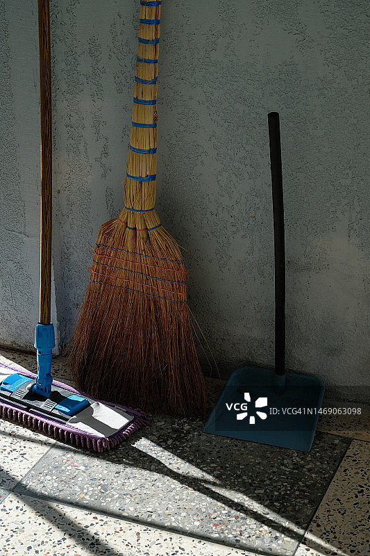 在干净的房间里，靠墙放着扫帚和垃圾铲。清洁地板的刷子。在家里、工作中、公共场所进行清洁。遵守秩序和符合卫生标准。清除建筑物内的灰尘和污垢图片素材