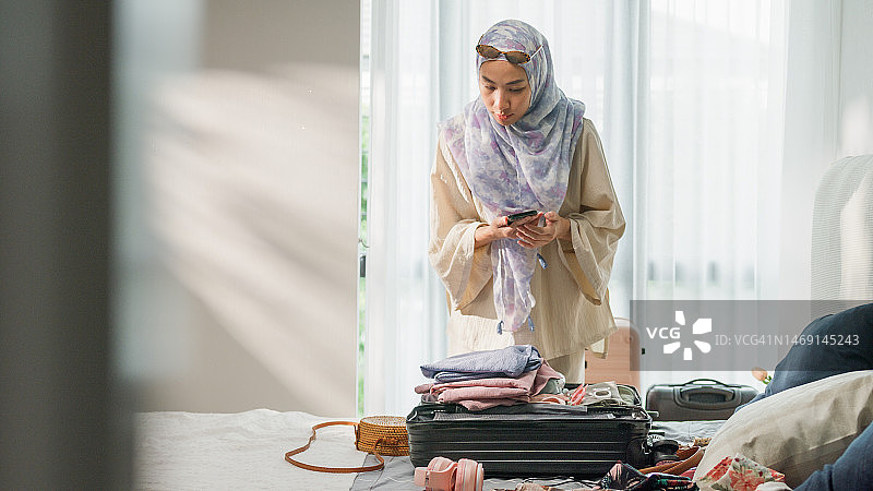 亚洲穆斯林女性卧室准备行李。图片素材