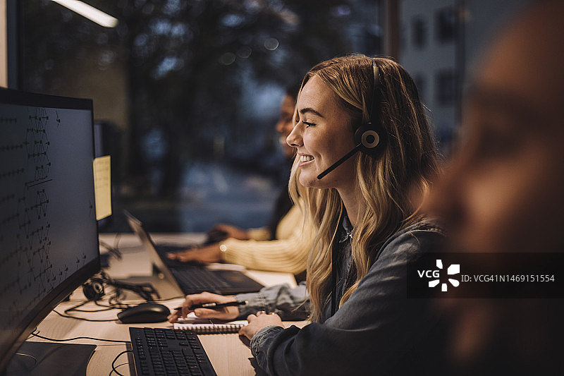 在呼叫中心使用电脑的微笑金发女客服代表图片素材