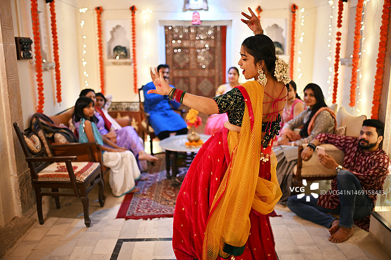 身穿传统Lehenga服饰的印度美丽女性在节日家庭庆祝活动中跳舞图片素材