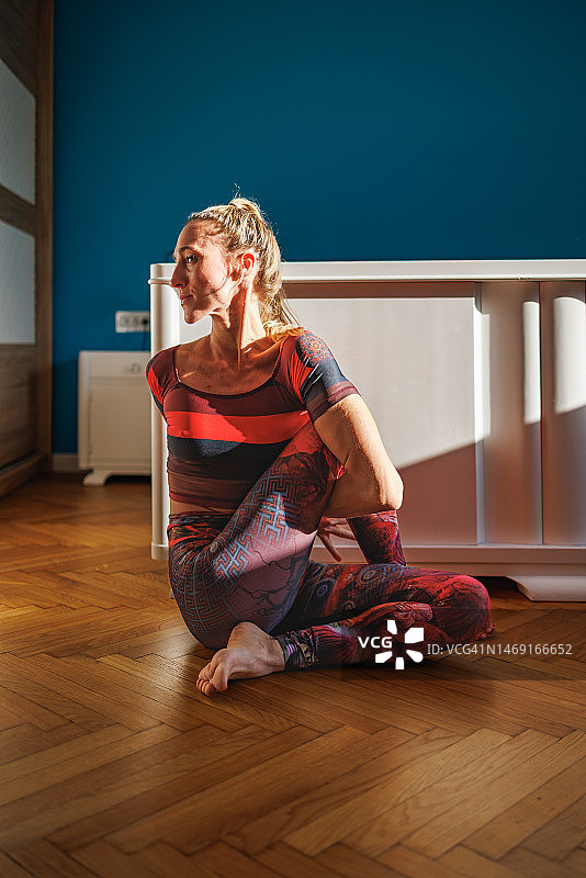 在家中做半坐扭转姿势瑜伽的女人图片素材