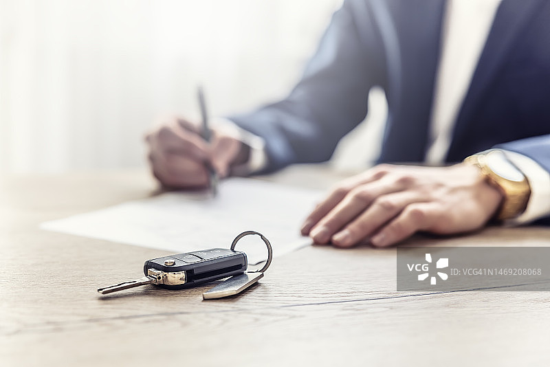 中介签署新车购买或租赁合同，前景是新车钥匙图片素材