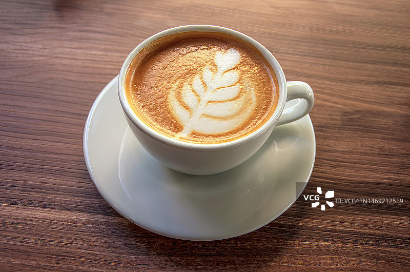 咖啡馆桌子上带有蕨类拉花图案的白色平白咖啡图片素材