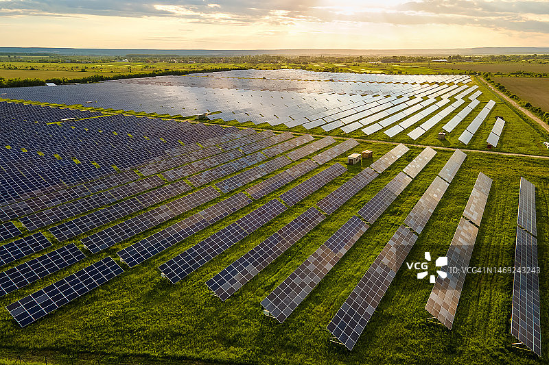 日出时分，大型可持续电力发电厂与太阳能光伏板阵列的航拍景色。零排放可再生能源概念。图片素材