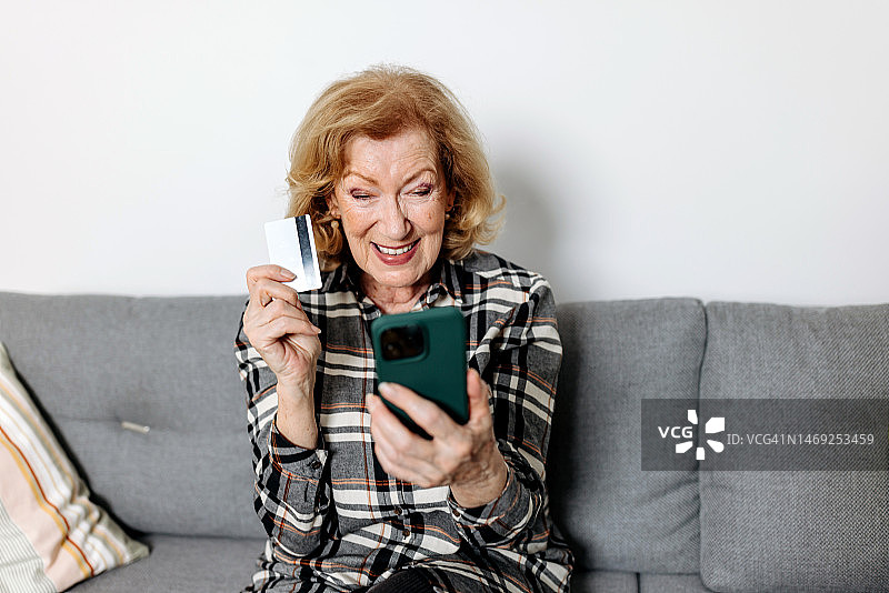 老年妇女使用手机和信用卡自信地管理财务图片素材