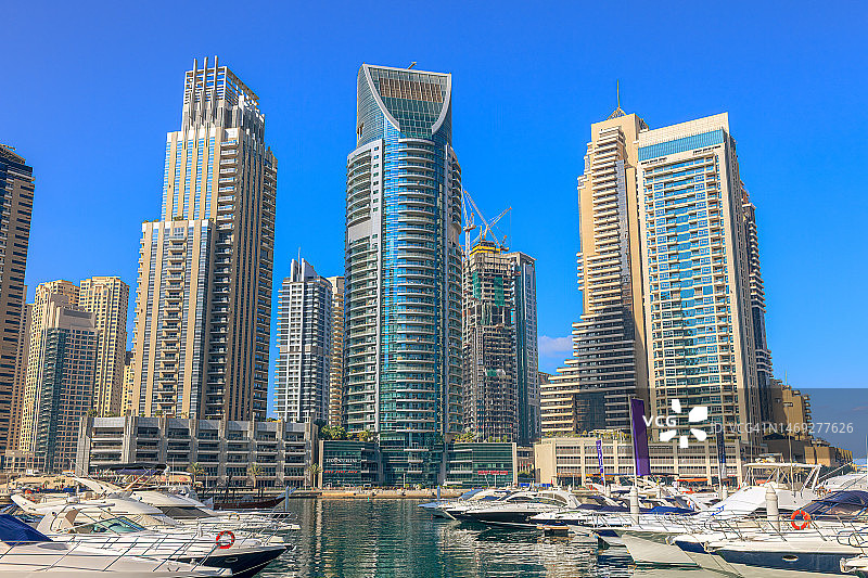 阿拉伯联合酋长国迪拜码头：停泊的船只与高耸的海滨摩天大楼图片素材