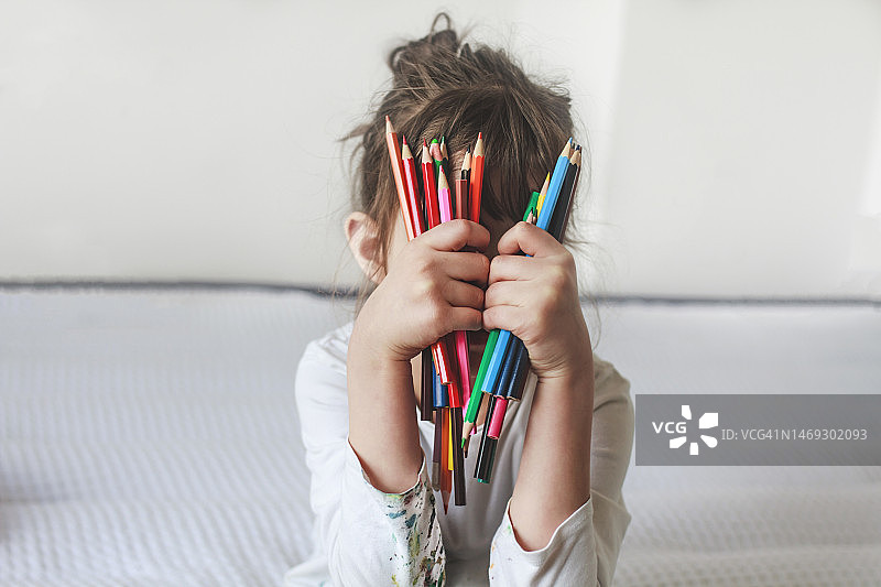 绘画后拿着铅笔遮住脸的女孩图片素材