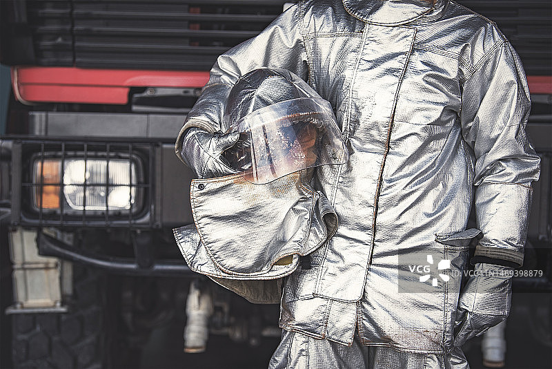 身穿防火服的男子站在消防车旁图片素材