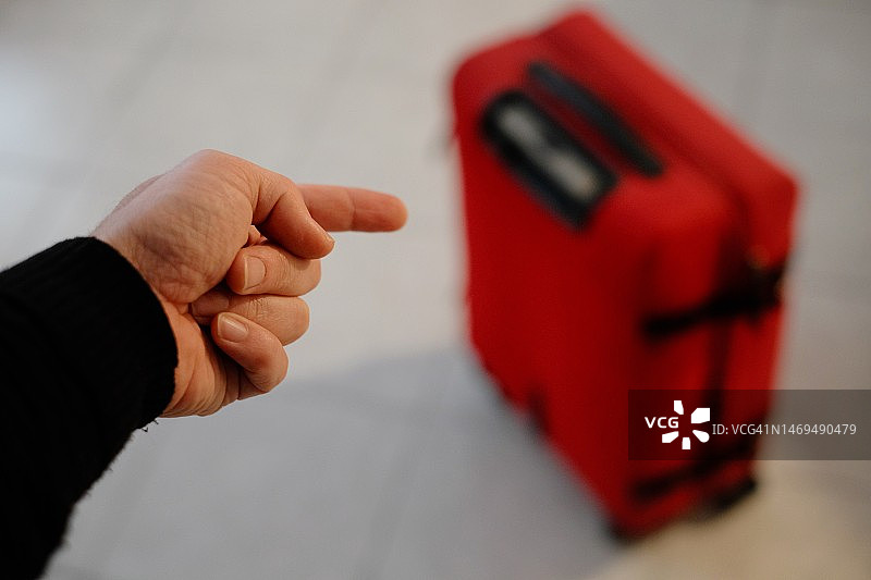 一只手指着的红色行李箱图片素材