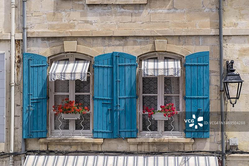 带有蓝色百叶窗和红色天竺葵的窗户，阿尔勒，普罗旺斯-阿尔卑斯-蓝色海岸，法国图片素材