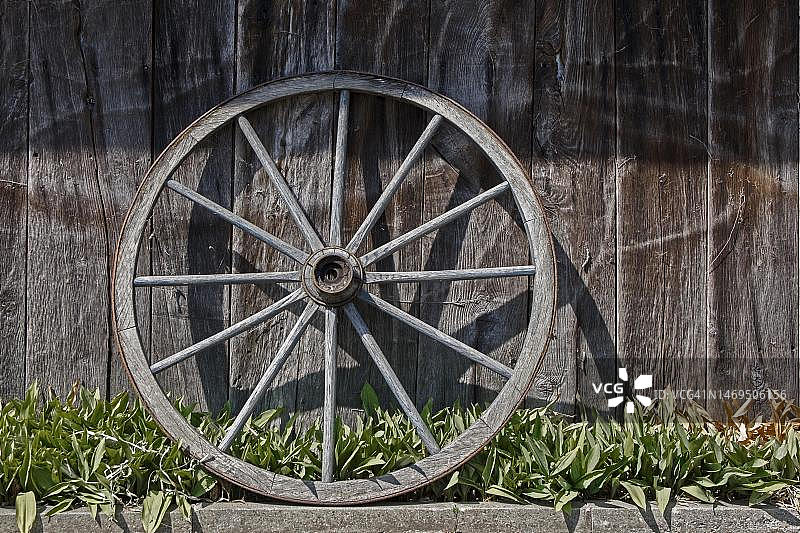 老式马车车轮，靠在谷仓墙上，明斯特兰，北莱茵-威斯特法伦，德国图片素材