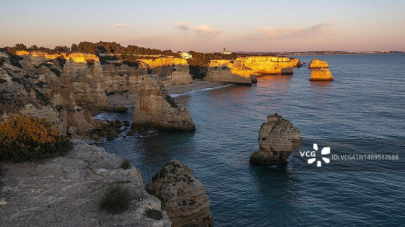 玛丽娜海滩日落鸟瞰，岩石和悬崖，葡萄牙阿尔加维陡峭的海岸图片素材