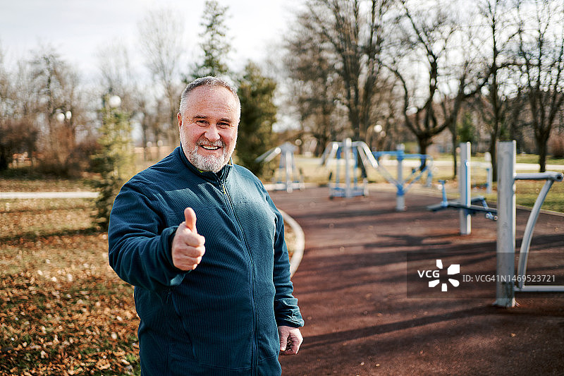 竖起大拇指的快乐中年运动员肖像图片素材