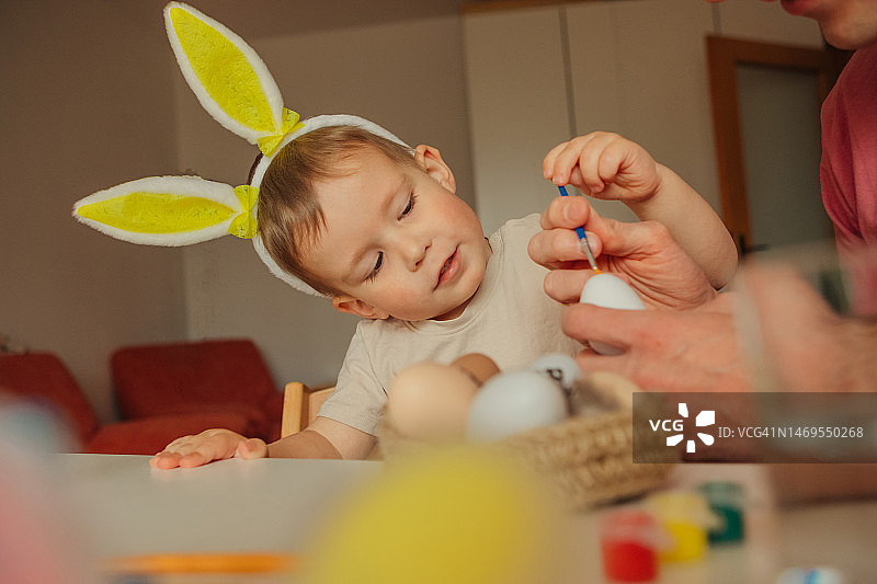 爸爸和孩子戴着兔子耳朵头饰装饰复活节彩蛋图片素材