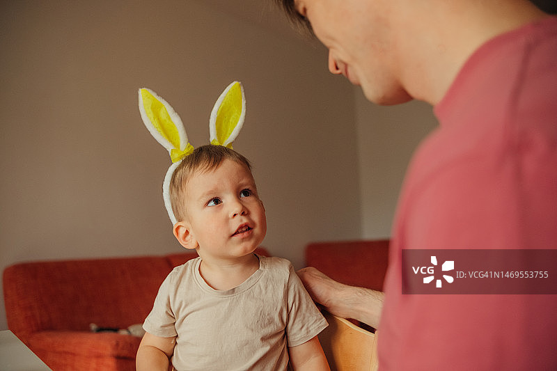 爸爸和孩子戴着兔子耳朵头饰装饰复活节彩蛋图片素材