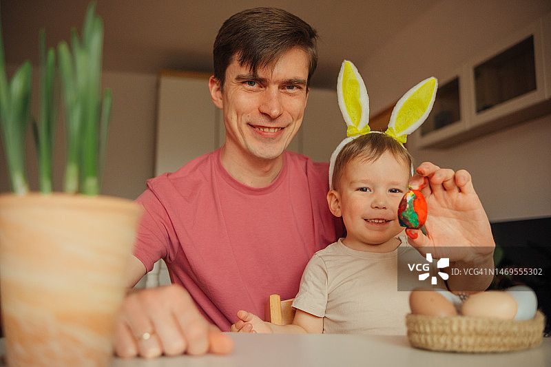 爸爸和孩子戴着兔子耳朵头饰装饰复活节彩蛋图片素材