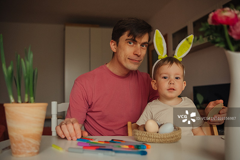 爸爸和孩子戴着兔子耳朵头饰装饰复活节彩蛋图片素材