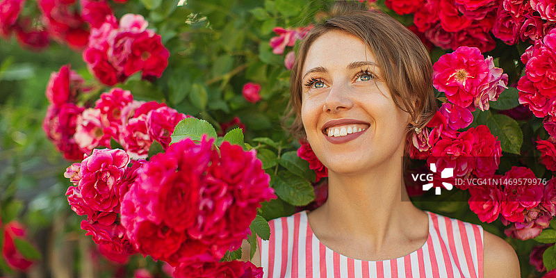 玫瑰丛背景下的金发女子图片素材