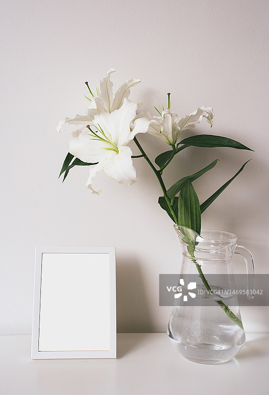 玻璃花瓶中的复活节百合花和空白相框，家居装饰细节图片素材