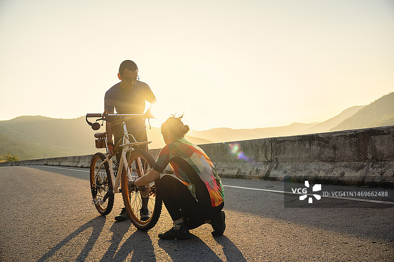 在泰国乡村道路上，情侣互相帮助准备自行车，享受假期图片素材