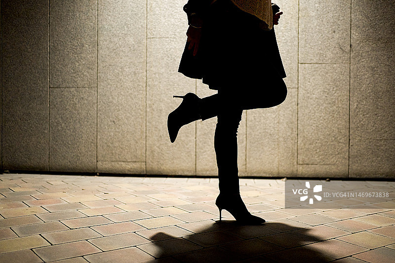 在街上行走的孤独女人的剪影和影子图片素材