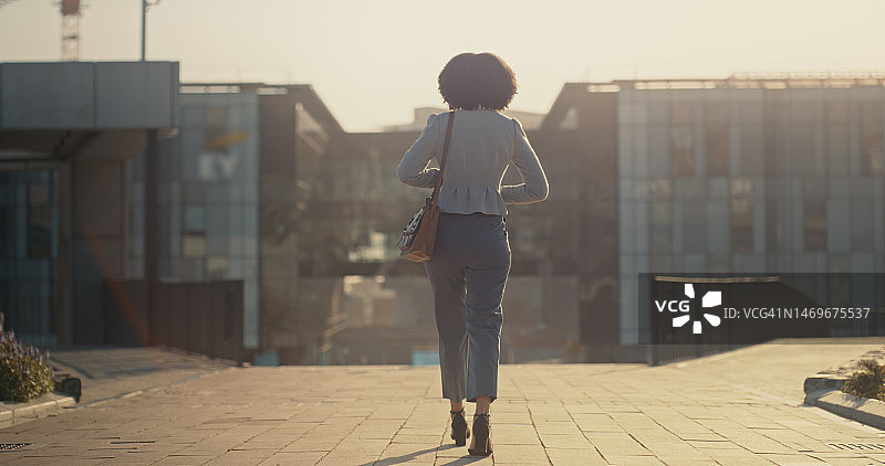 行走，旅行和在城市的商务女性的背影，为了早晨上下班工作，公司职业和工作。旅行，旅程和在城市街道上的女性工人步行到日落时分的办公楼图片素材