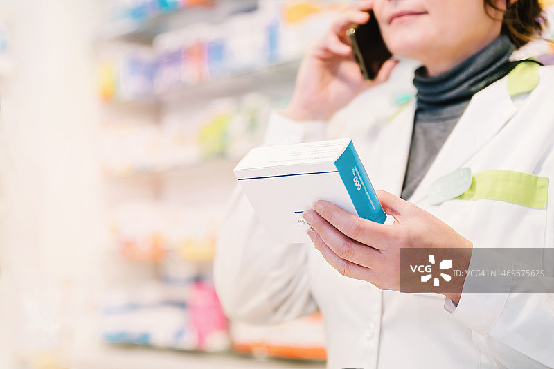 药剂师拿着药，同时在打电话图片素材