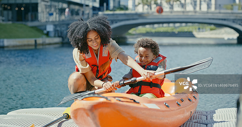 母亲在瑞典的河流或湖泊上教孩子划桨、皮划艇和水上运动，在快乐的夏季冒险中享受假期。旅行，度假和黑人妇女与儿子在城市运河中划独木舟图片素材