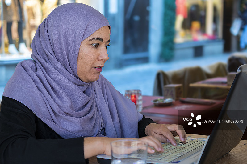 戴着头巾使用笔记本电脑的穆斯林女性特写图片素材