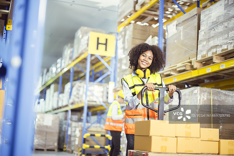 仓库里的非洲裔女员工，轮椅和货架上的眼科检查产品包装盒图片素材