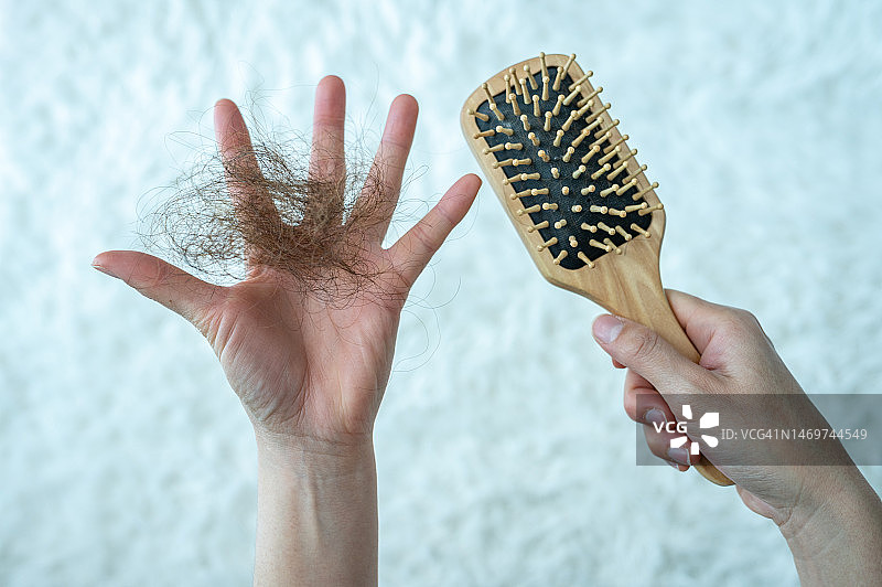 女子梳头后手持梳子，头发凌乱脱落的特写照片图片素材