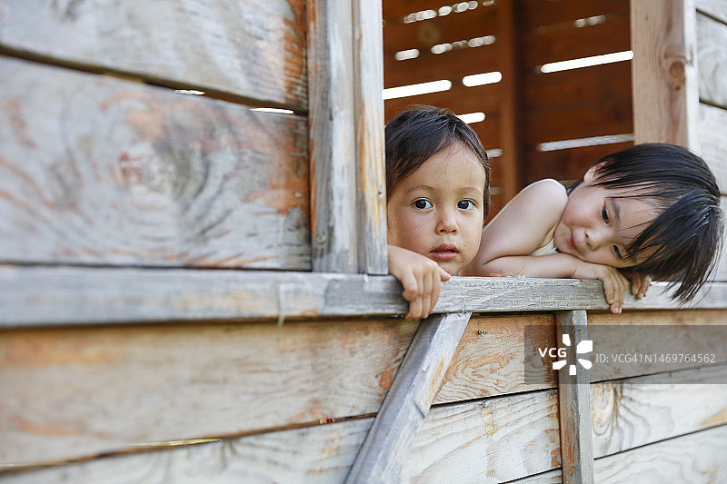 两个孩子在小木屋窗口向外看图片素材