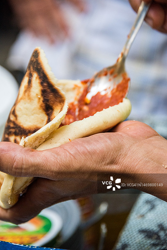 在皮塔饼上涂抹哈里萨辣酱制作突尼斯油炸三明治图片素材