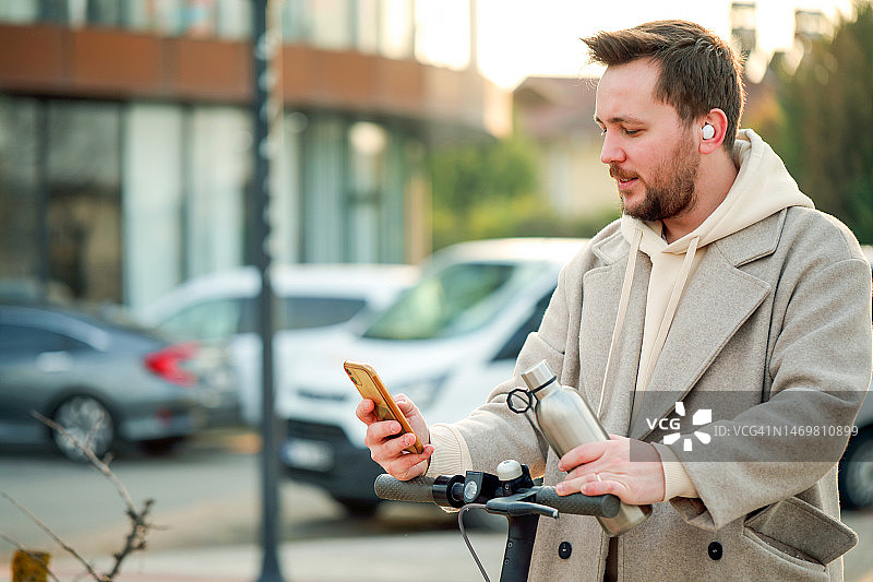 在城市中使用无线耳机、滑板车享受科技与可持续能源：打电话和听音乐图片素材