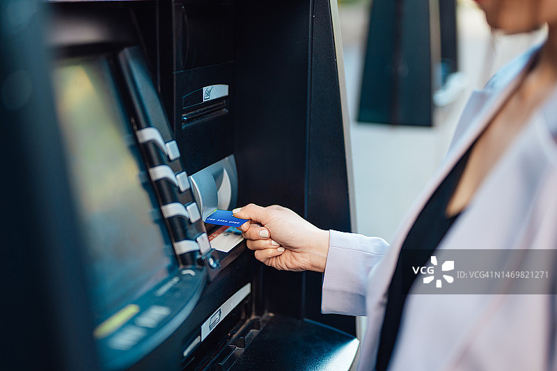 年轻女子将银行卡插入自动取款机特写图片素材