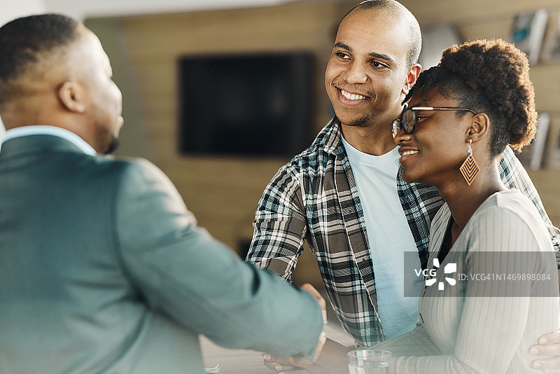 快乐的黑人夫妇在办公室与经纪人达成协议。图片素材