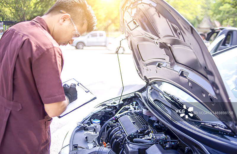 汽车服务、维修、保养与人员概念——工作人员正在调查不粘发动机启动的问题。图片素材