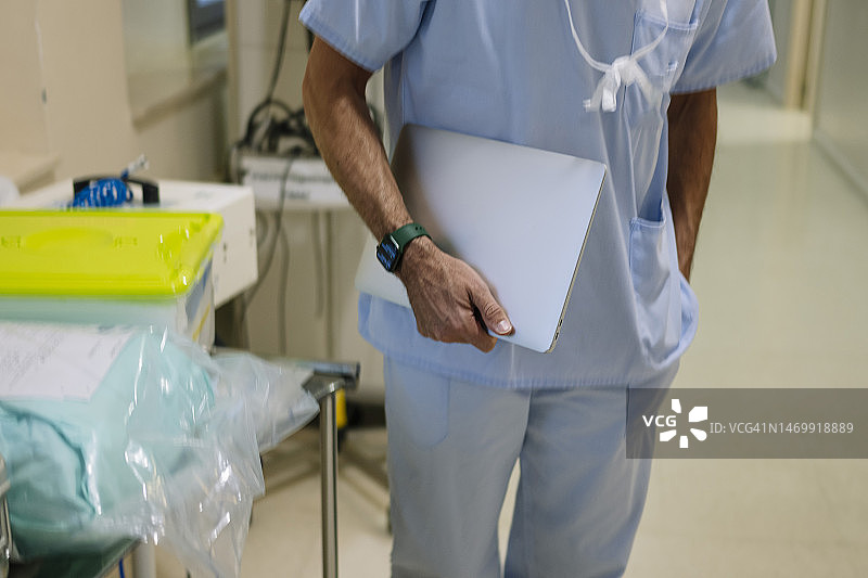 无法辨认的医生在医院走廊里使用笔记本电脑图片素材