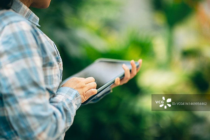 女农民使用移动设备检查农场植物的状况图片素材