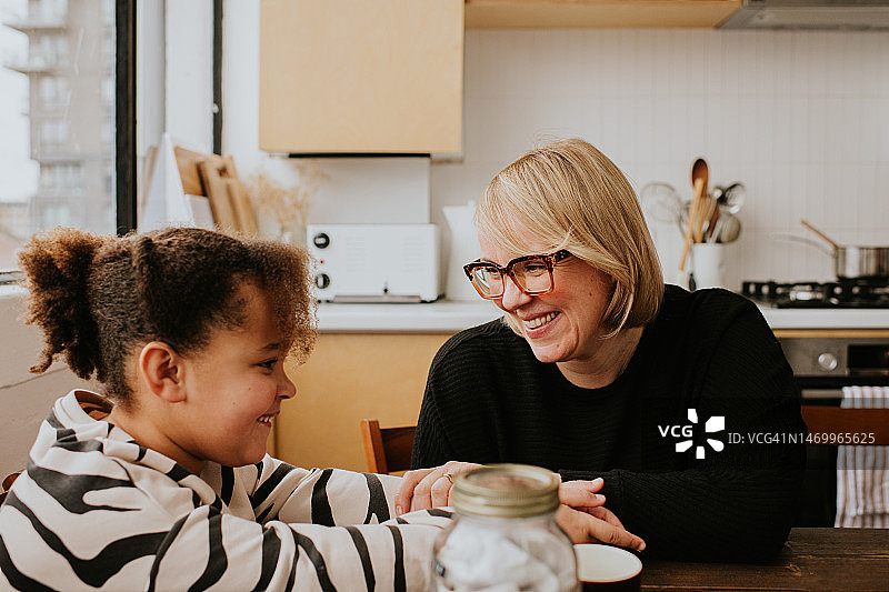 女人俯身看着女儿，充满爱意地微笑图片素材