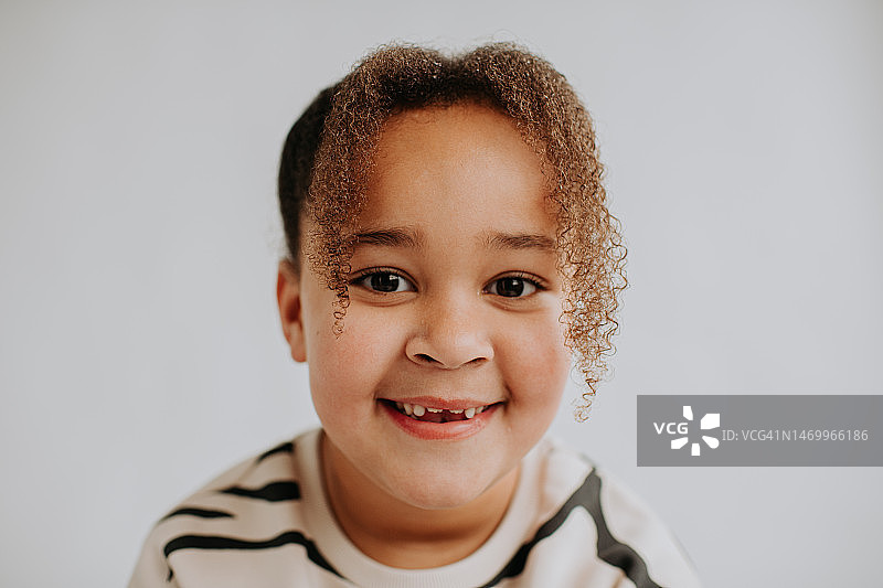 特写：白色背景下混血小女孩看向镜头微笑图片素材