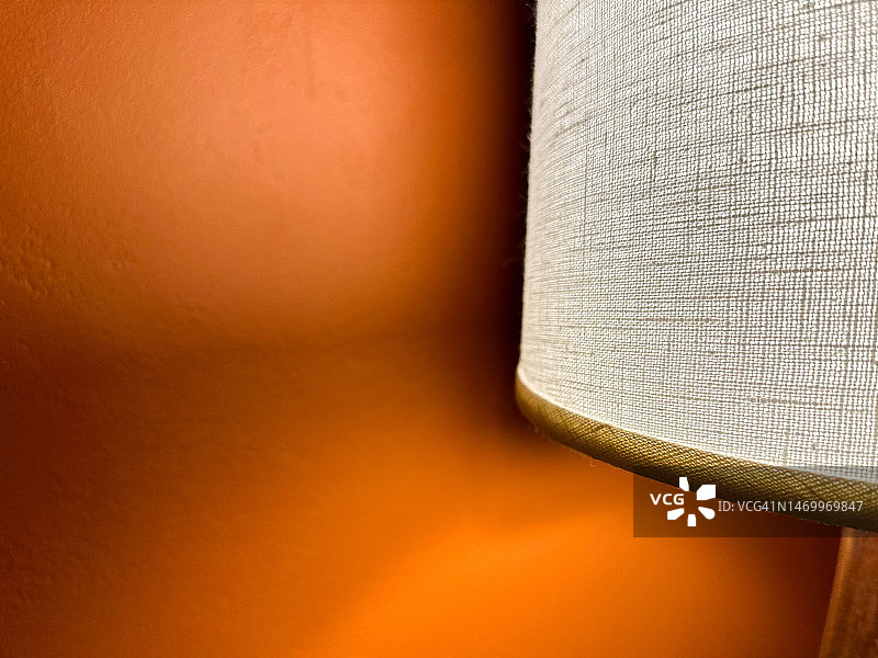 与鲜艳橙色色调的彩绘墙形成对比的照明灯罩图片素材