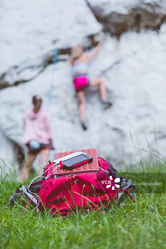 充电宝和背包，背景是正在攀岩的女性图片素材