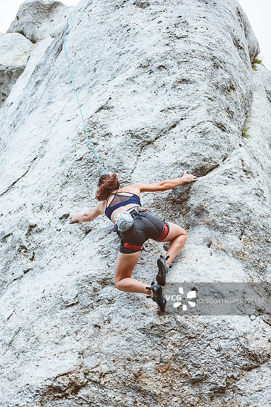 年轻女子攀登悬崖岩石图片素材
