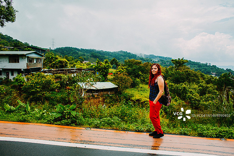 雨天路边看着镜头的长发红发女人图片素材