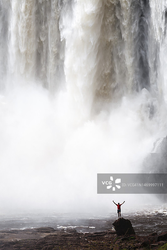 男子站在岩石上，面前是阿蓬瓦奥瀑布图片素材
