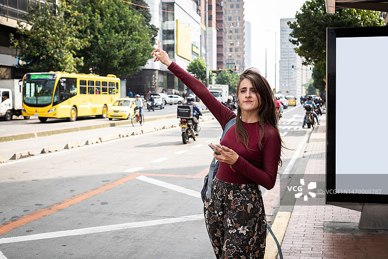 年轻女子在户外公交车站招手拦出租车／公交车图片素材