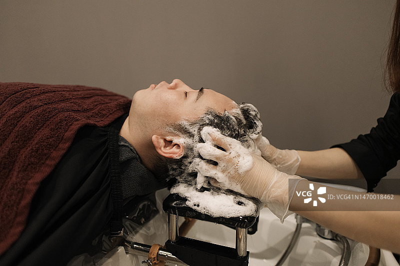 理发师正在为一位男士洗头和按摩头部图片素材