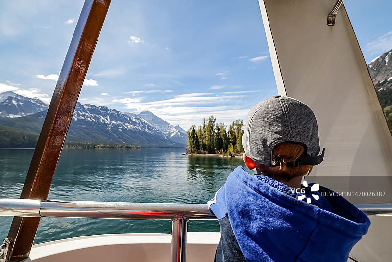 在加拿大艾伯塔省沃特顿湖国家公园沃特顿湖上乘船游览的男孩图片素材