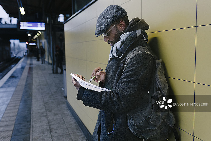 候车时阅读笔记本的中年学生图片素材